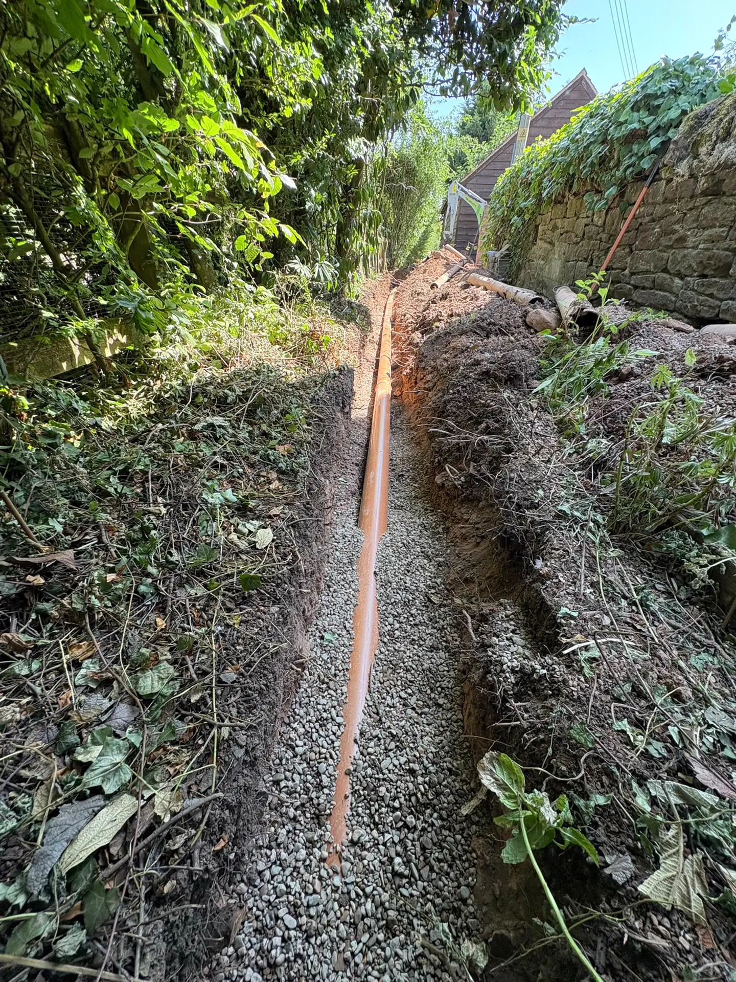New drainage pipe bedded on washed shingle in an open trench
